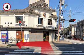 商店街のアーケードをくぐり抜けた所にある信号を渡って、左折してください。